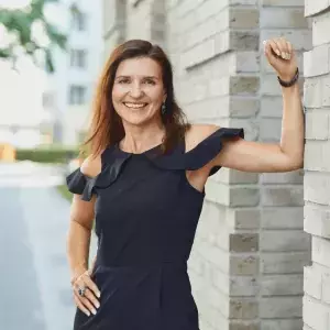 Tanja Schramm, CEO MEET GERMANY, lächelt und lehnt sich an eine Wand an